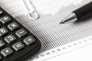 Calculator and pen resting on a table, symbolizing calculating software costs and budgets.