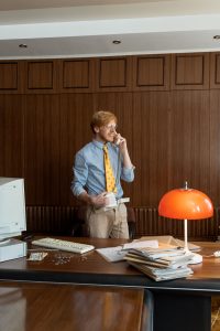A man having a phone call at his office desk, representing following up with a prospective client.